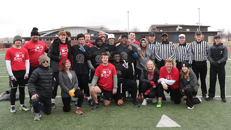 A group of people stand on a football field, posing for a picture. 