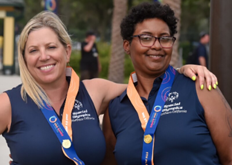 Two women standing side by side with their arms around one another shoulders. 