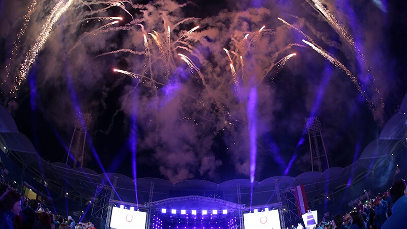 Fireworks going off in the sky as spectators watch and celebrate. 