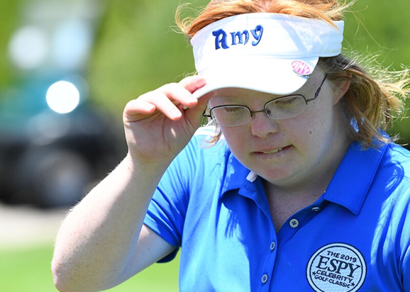 Close up of Amy adjusting her sun visor that has her name on it.