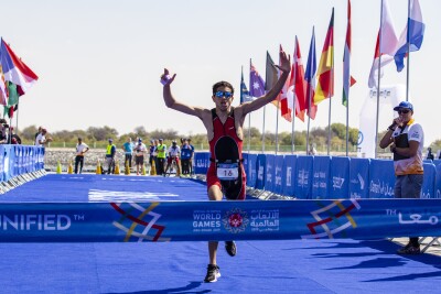 Male triathlete about to cross the finish line while celebrating already with his hands up