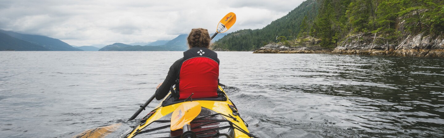 Female kayaker paddling into the openness of the lake.  