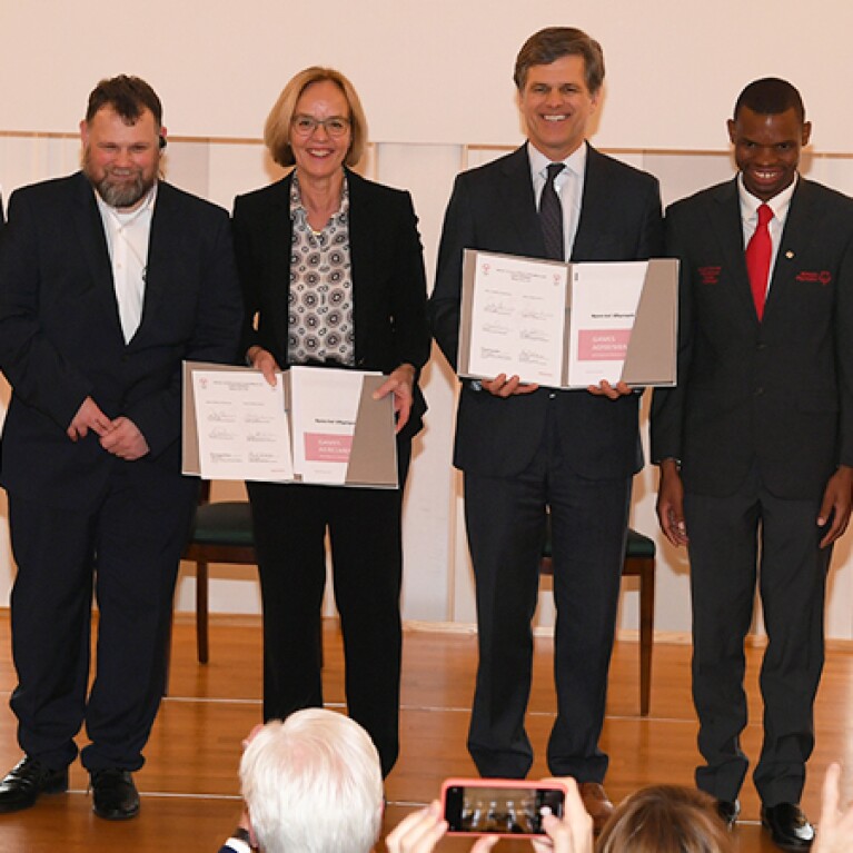 Six Special Olympics representatives standing on stage holding the Berlin signing and posing for group photos. 