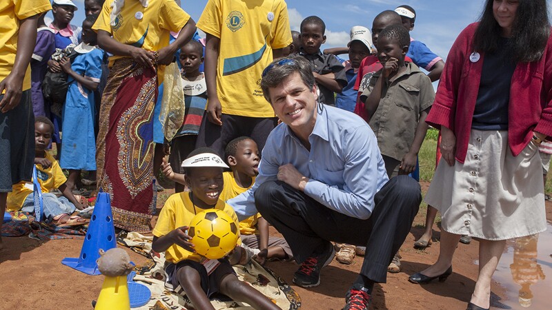 Dr. Timothy Shriver posing outside with a few young athletes and adults. 