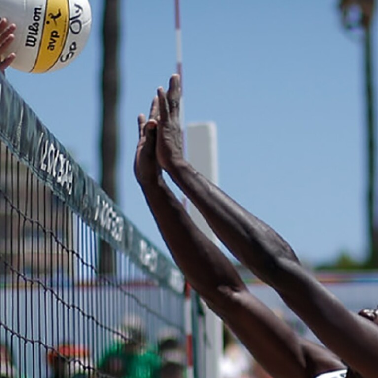 Two athletes jumping for the volleyball. 