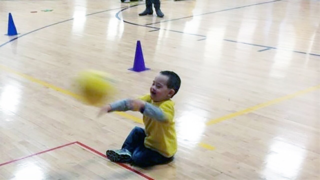 Baur throws ball in air while sitting on the floor.)